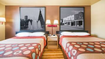 A hotel room with two beds, a nightstand with lamps, and two framed pictures on the wall.