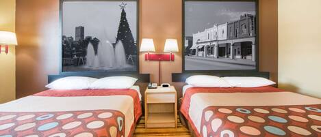 A hotel room with two beds, a nightstand with lamps, and two framed pictures on the wall.