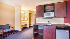 A compact kitchenette with a microwave, sink, and a built-in refrigerator.