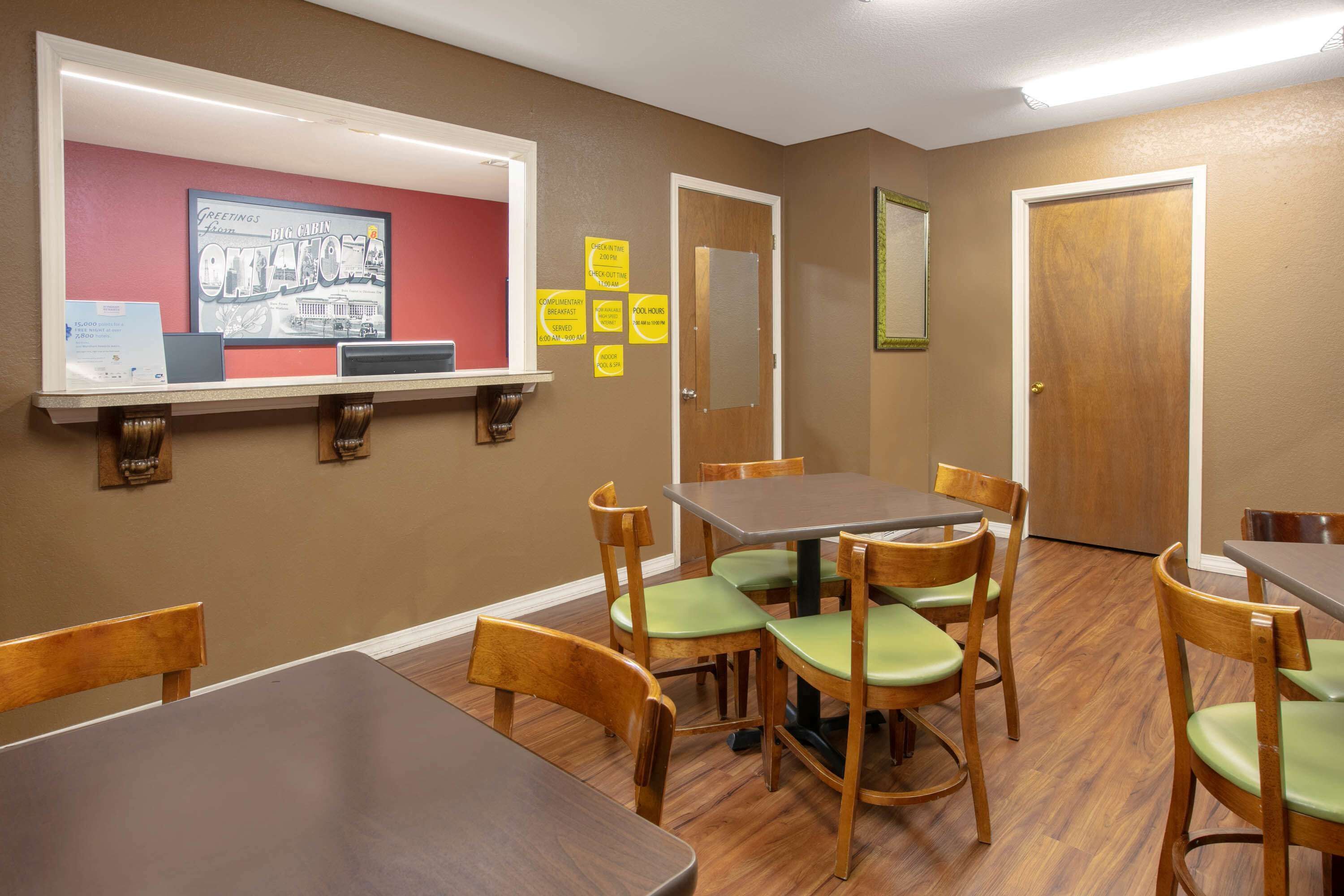 Un comedor con mesas y sillas de madera, un tablón de anuncios con notas y un cuadro en la pared.