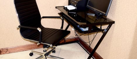 Un bureau d’angle aménagé avec un fauteuil pivotant, un ordinateur de bureau et une imprimante posés sur le bureau.