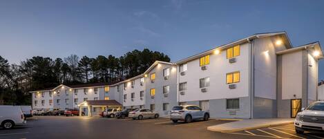 A multi-story hotel with a parking lot and several cars parked in front.