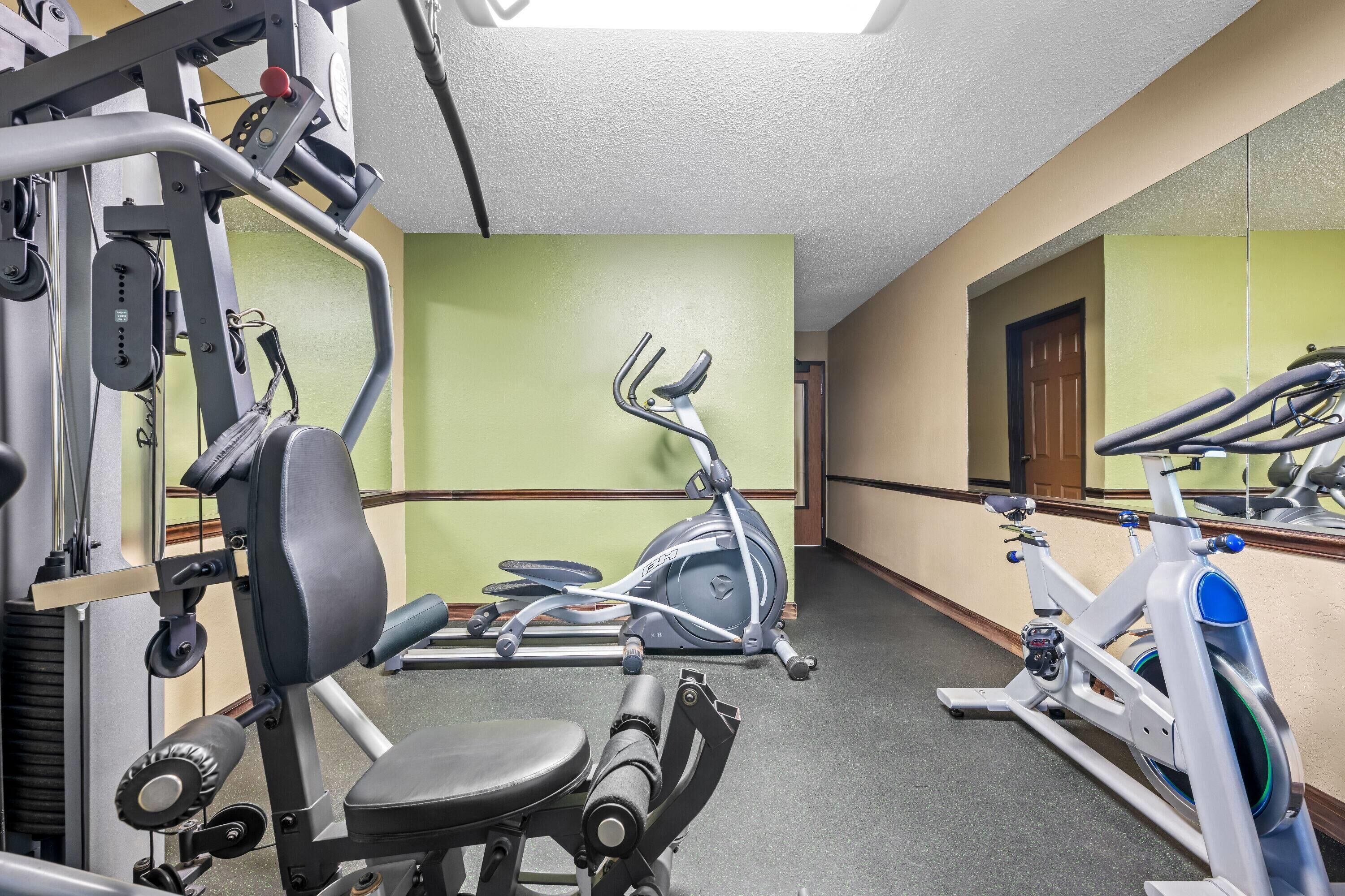 Un gimnasio con equipo de ejercicio, un espejo y una pared verde.