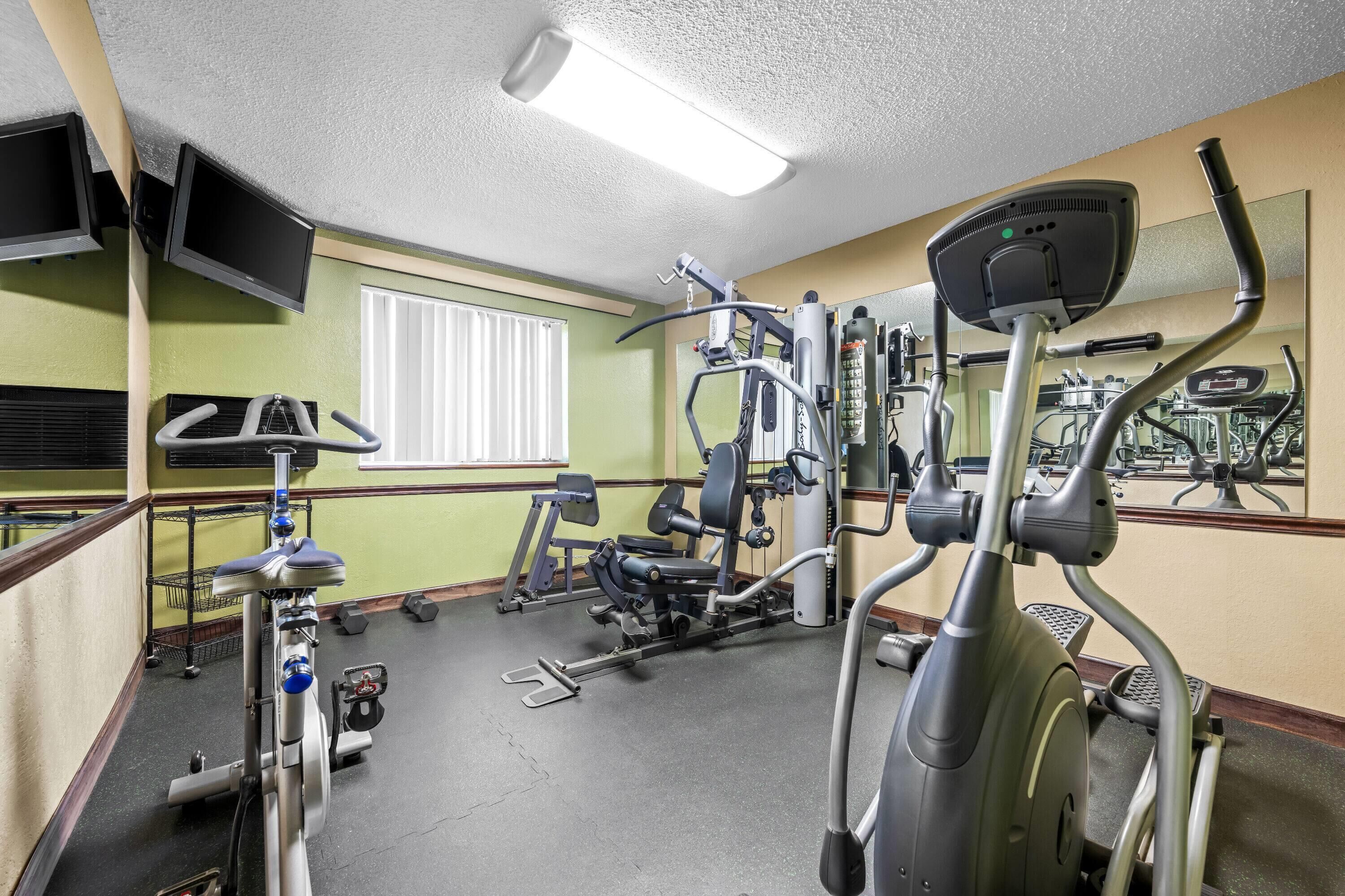 Academia com equipamentos de ginástica, televisão e janela.