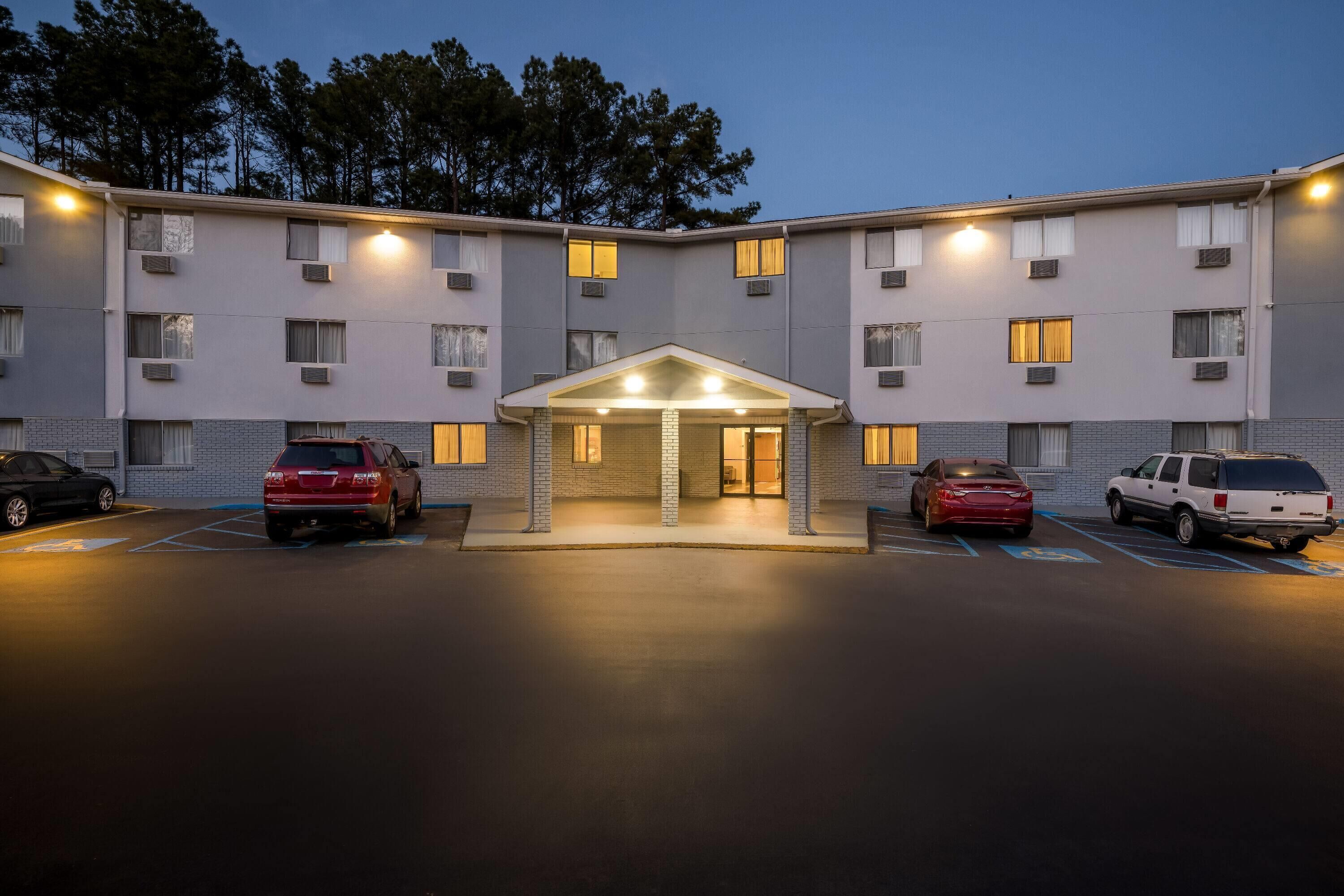 Un hôtel à plusieurs étages, doté d’une entrée principale, d’un parking et d’un toit plat.
