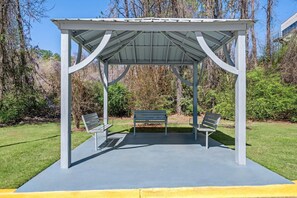 Un'area relax esterna coperta, con panche e una struttura a pergola.