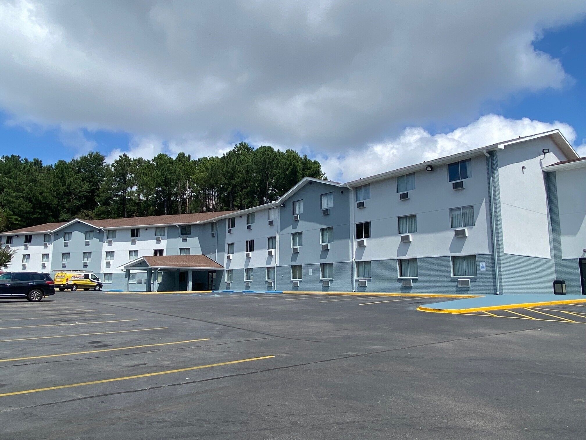 Un motel de varios pisos con un estacionamiento al frente.