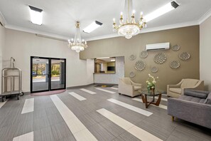 Un vestíbulo amplio con candelabro, zona de estar y mostrador de recepción.