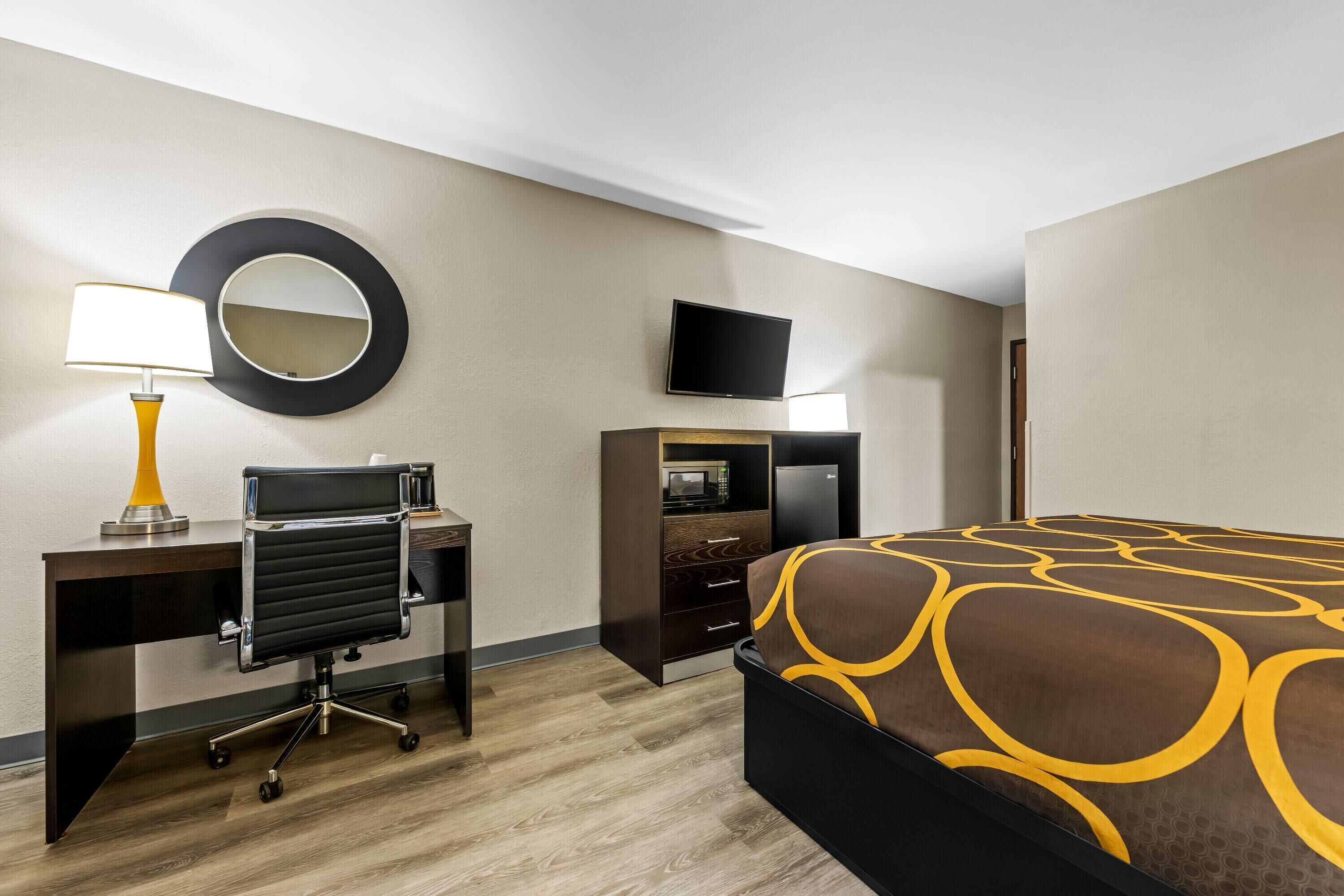 Habitación de hotel con cama, escritorio, silla, televisor y microondas.