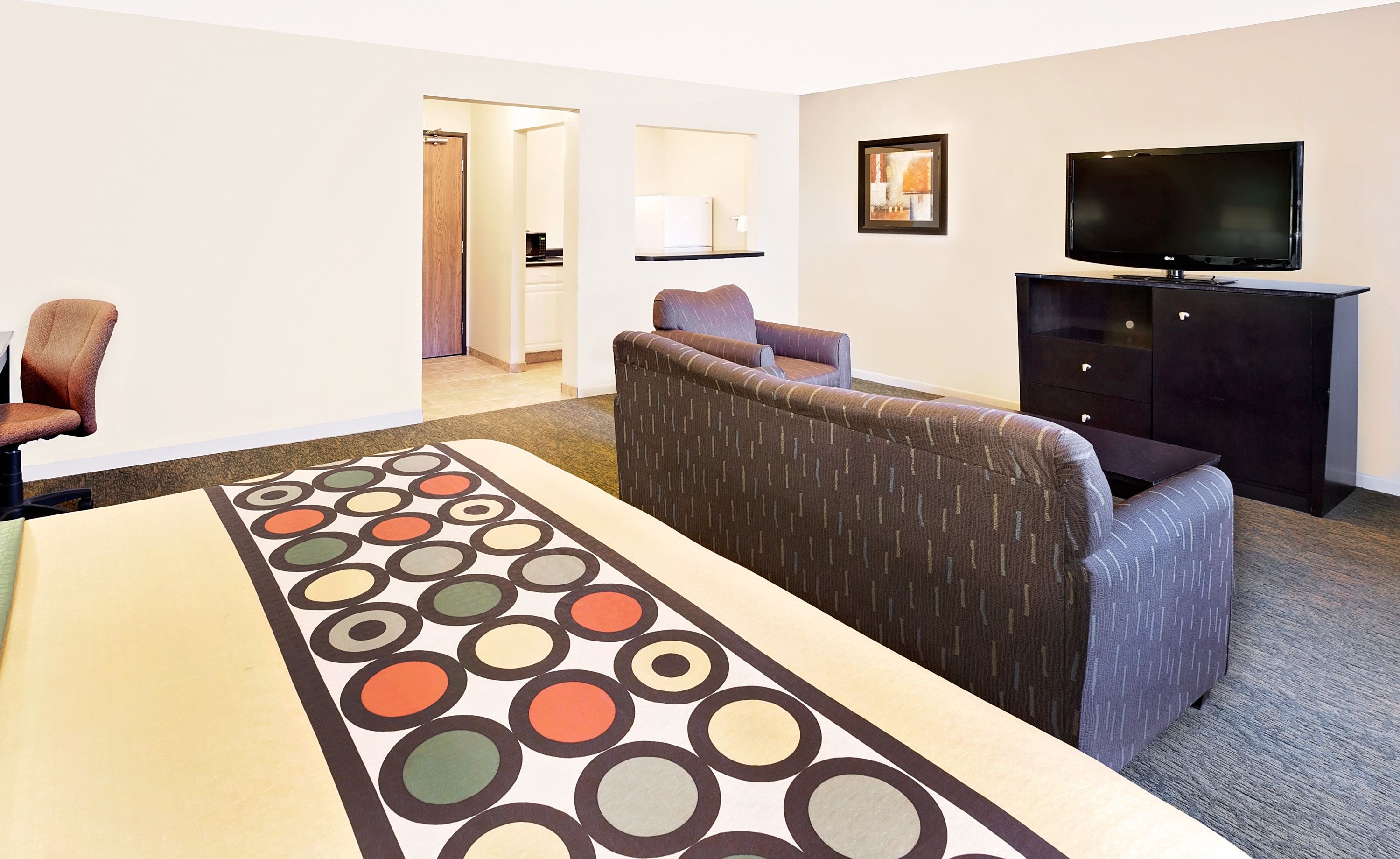 A hotel room with a large bed, a TV, a dark wooden cabinet, and a patterned rug.