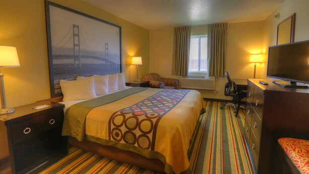 A hotel room with a bed, a desk, a chair, a television, and a window with curtains. - Super 8 by Wyndham Mt. Pleasant (Mount Pleasant)