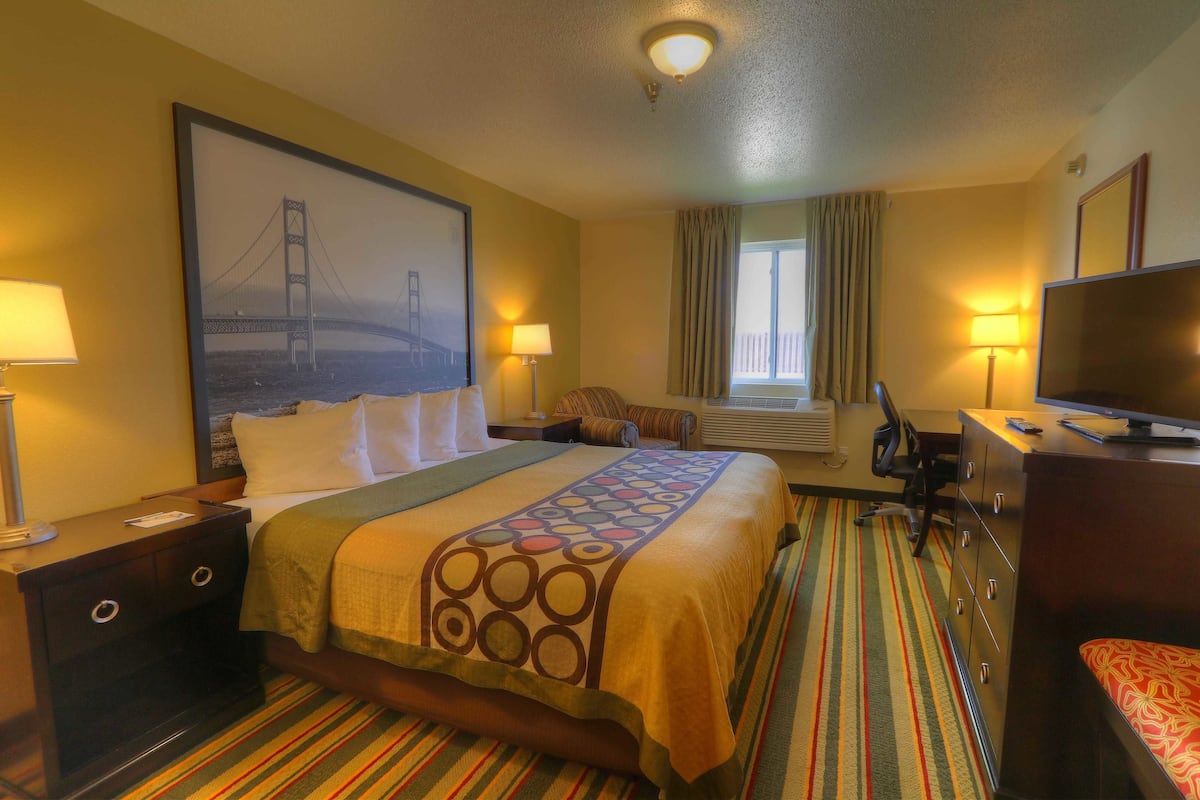 A hotel room with a bed, a desk, a chair, a television, and a window with curtains.