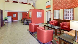 A lobby with red upholstered chairs, a glass-top table, and a patterned carpet. - Super 8 by Wyndham Mt. Pleasant (Mount Pleasant)