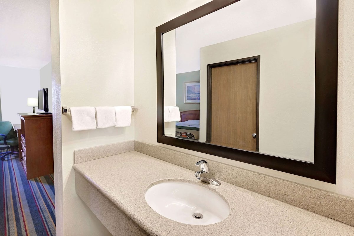 A hotel bathroom with a sink, mirror, and towel rack.