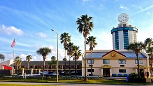 A hotel with a prominent tower, palm trees, and an American flag. - Orlando Inn International Drive Area (Orlando)