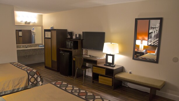 A hotel room with two beds, a desk, a chair, a TV, a lamp, and a bench. - Orlando Inn International Drive Area (Orlando)