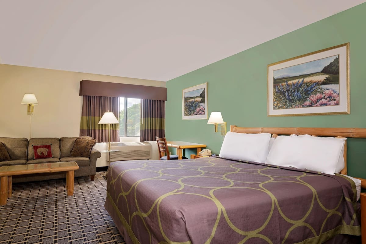 Una habitación de hotel con una cama grande, un sofá, un escritorio y dos cuadros en la pared.
