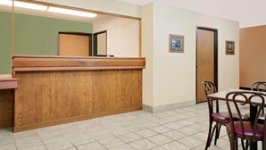 A reception area with a wooden counter, a mirror, and a tiled floor. - Super 8 by Wyndham Cloquet (Cloquet)