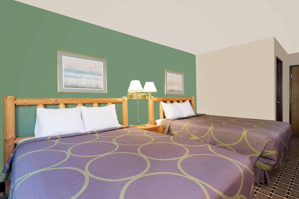 Habitación de hotel con dos camas, paredes verdes y cuadros enmarcados.