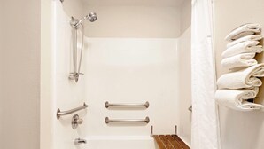 A bathroom with a bathtub, grab bars, a showerhead, and a towel rack. - Super 8 by Wyndham Cloquet (Cloquet)