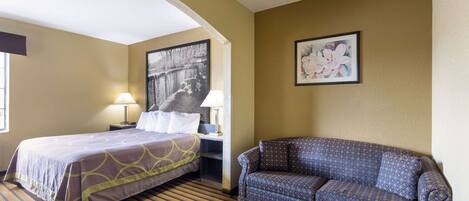 Een hotelkamer met een bed, een slaapbank, een lamp en twee foto's in lijsten aan de muur.