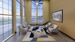 A spacious room with large windows, a ceiling fan, and a patterned rug. - Super 8 by Wyndham Nixa/Springfield Area (Nixa)