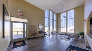 A spacious lobby with a wooden floor, large windows, a reception desk, and seating area. - Super 8 by Wyndham Nixa/Springfield Area (Nixa)
