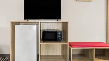 Una kitchenette con refrigerador, microondas y un televisor de pantalla plana sobre una repisa de madera.
