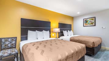 Habitación de hotel con dos camas, una silla, una lámpara y un cuadro en la pared.