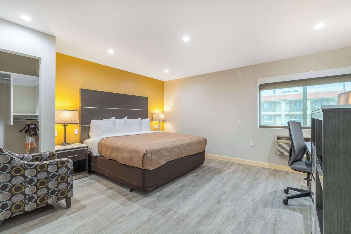 Habitació d'hotel moderna amb un llit gran, taulells laterals, escriptori amb cadira i un armari.