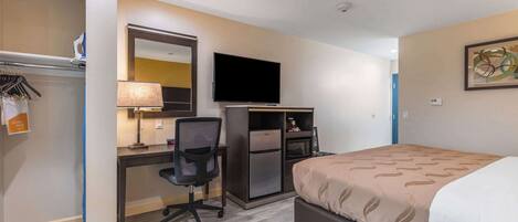Ein Hotelzimmer mit Bett, Schreibtisch, Stuhl, Fernseher und Mikrowelle.