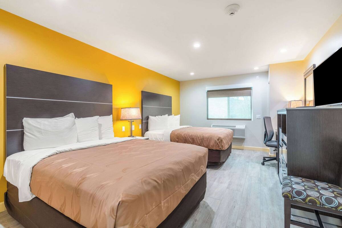 Habitació d'hotel amb dos llits, una taula i una cadira.