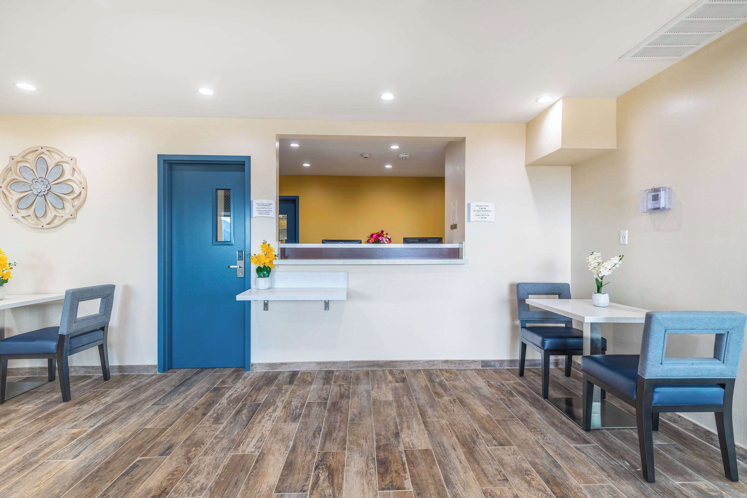 A reception area with a blue door, a white reception desk, and two blue chairs.