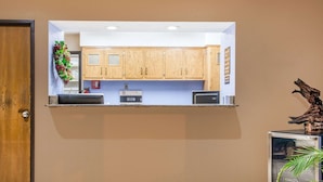 Una cocina con armarios de madera, microondas empotrado y un refrigerador pequeño.