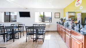 A restaurant with a counter, chairs, and a TV on the wall.