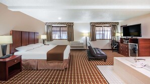 A hotel room with a bed, a sofa, a desk, a TV, and a bathroom.