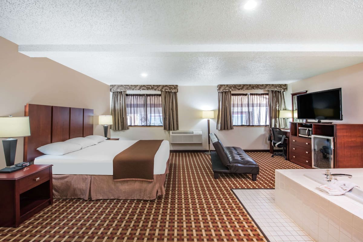 A hotel room with a bed, a sofa, a desk, a TV, and a bathroom.