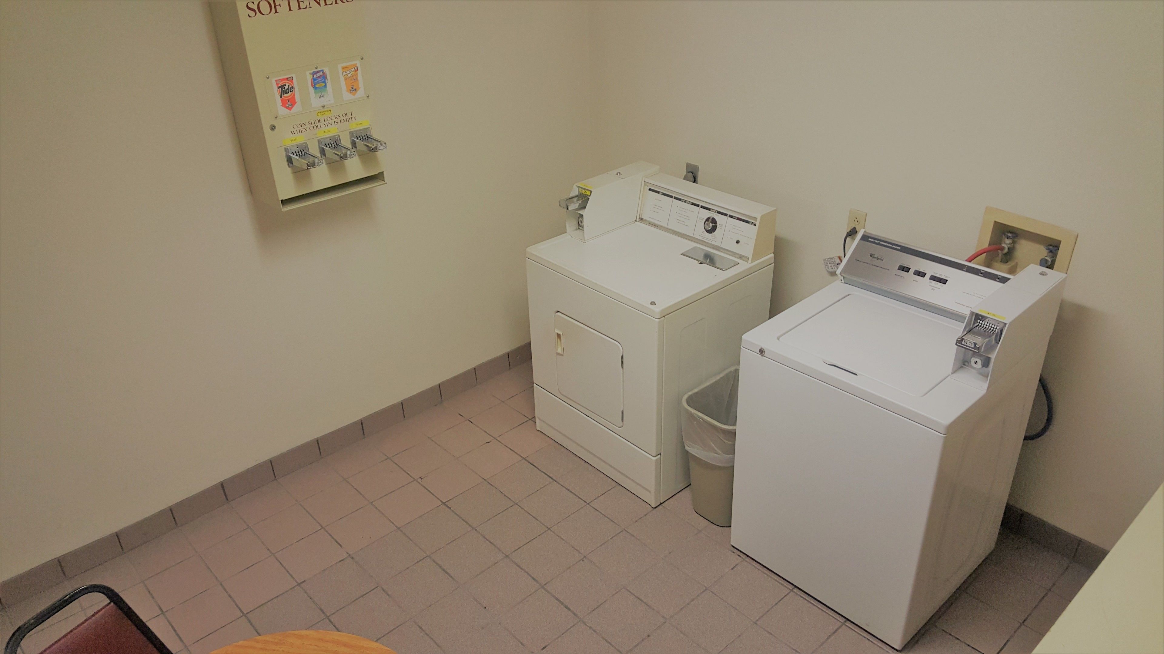 A laundry room with two washing machines and a coin-operated dryer.
