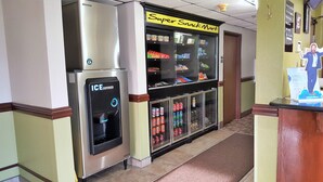 A vending machine labeled "Super Snack Mart" with various snacks and beverages, an ice dispenser, and a Coca-Cola cooler.