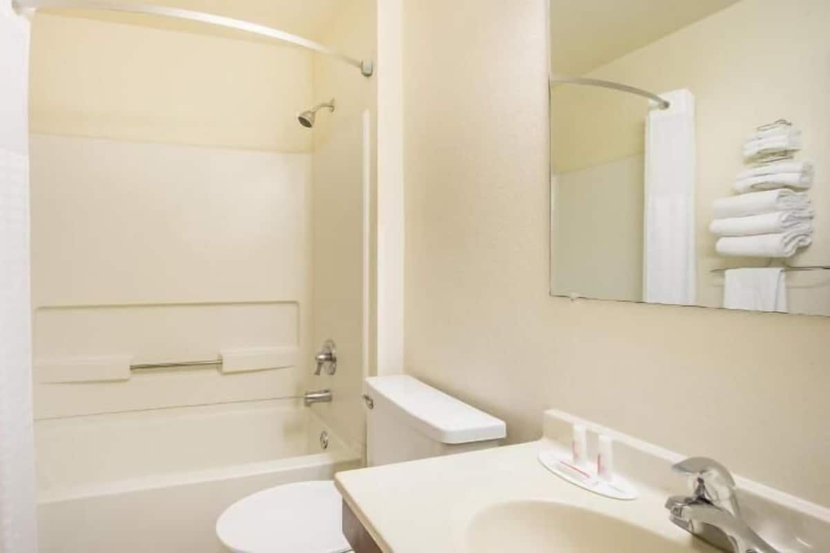 A bathroom with a bathtub, toilet, sink, and a mirror.