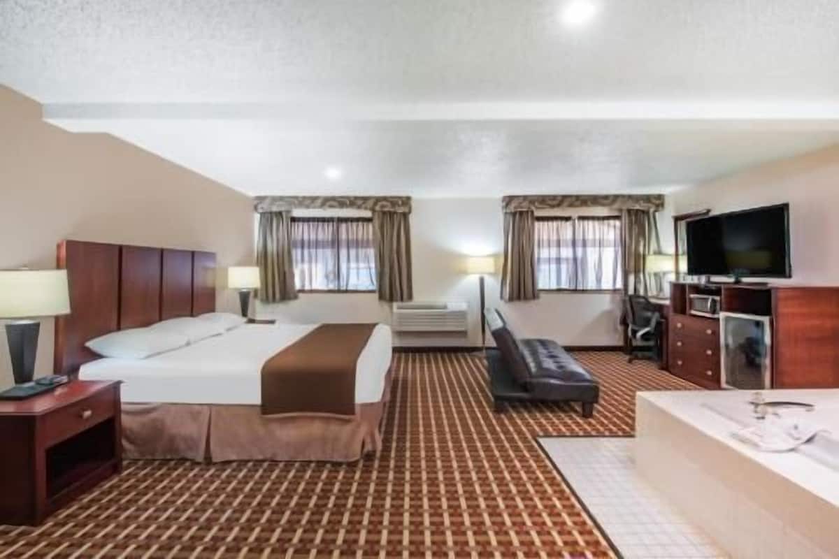 A hotel room with a bed, a desk, a chair, a television, and a window.