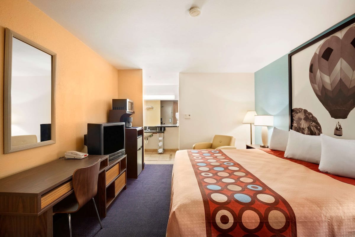 A hotel room with a bed, desk, chair, television, and a large mirror.