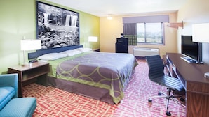 Hotelkamer met een bed, bureau, stoel, televisie en een groot raam met uitzicht.