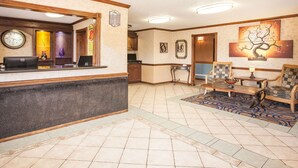 Een receptiezone met een receptiebalie, een klok en een zithoek met een salontafel en stoelen.