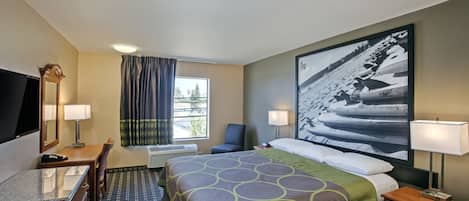 A hotel room with a bed, a desk, a chair, a TV, a window with curtains, and a large framed picture on the wall.