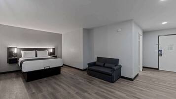 A modern hotel room with a bed, a sofa, and a door.
