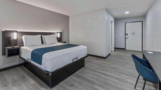 Una habitación de hotel moderna con cama, mesita de noche y escritorio con silla.