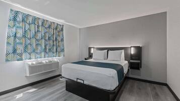Une chambre d’hôtel moderne, équipée d’un lit, d’un radiateur fixé au mur et d’un rideau à motifs.