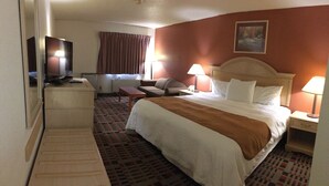 Une chambre d’hôtel avec un lit, un bureau, une télévision et une fenêtre avec des rideaux.