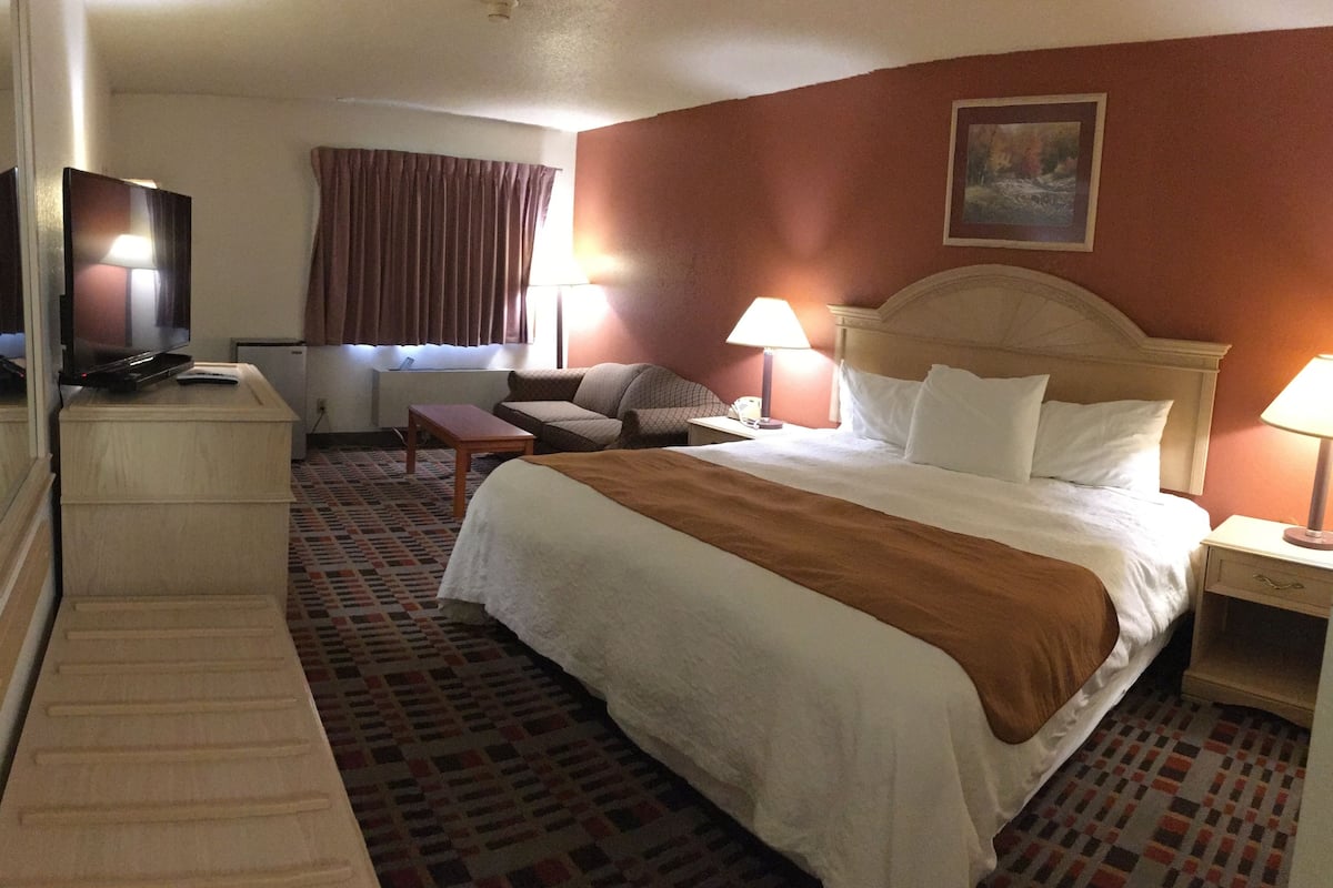 Une chambre d’hôtel avec un lit, un bureau, une télévision et une fenêtre avec des rideaux.